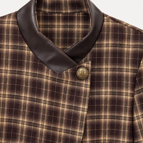 Detalle del cuello y el botón dorado de la chaqueta de cuadros